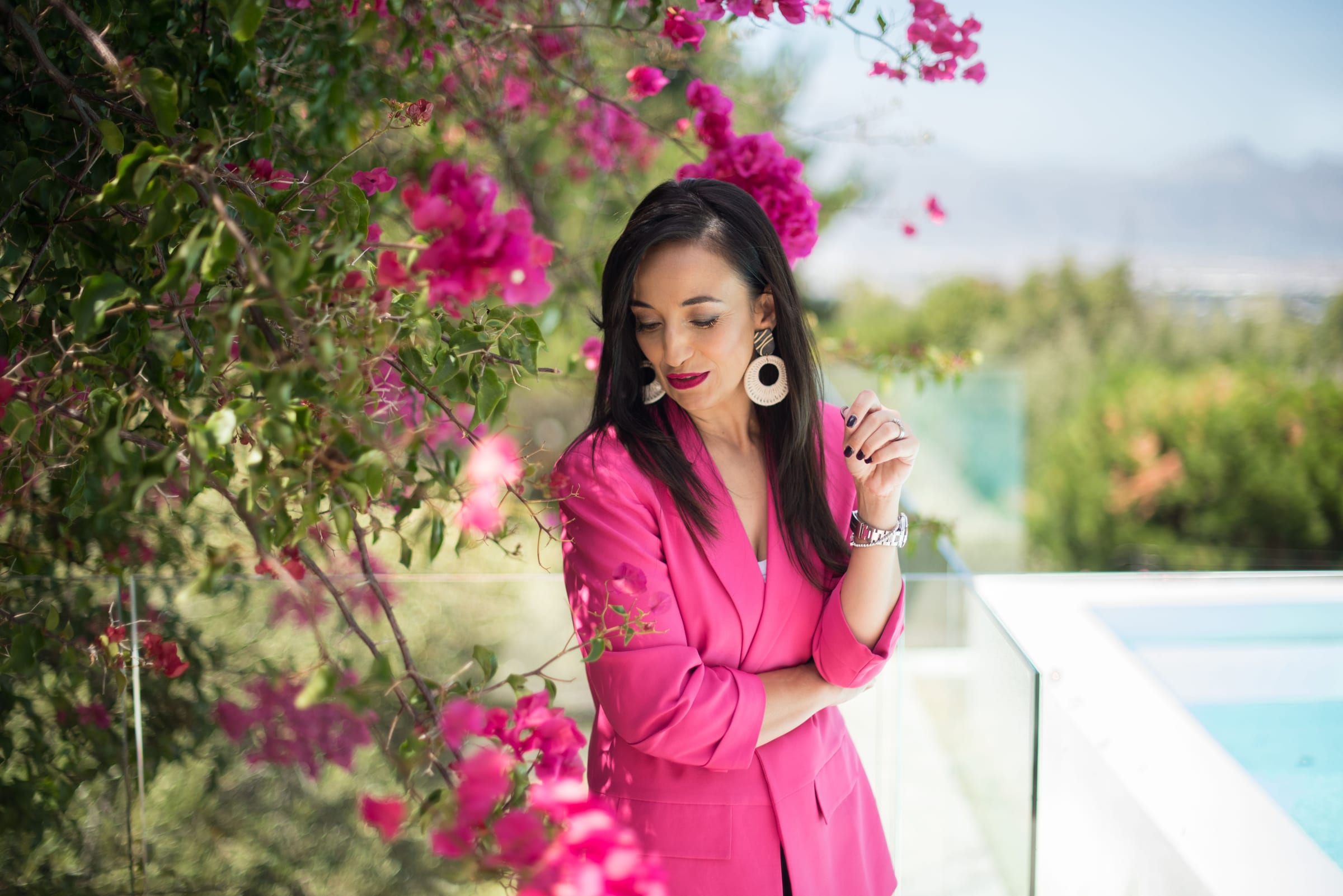 Woman in a hot-pink blazer with statement earrings beside bougainvillea — fashion photography in Cape Town