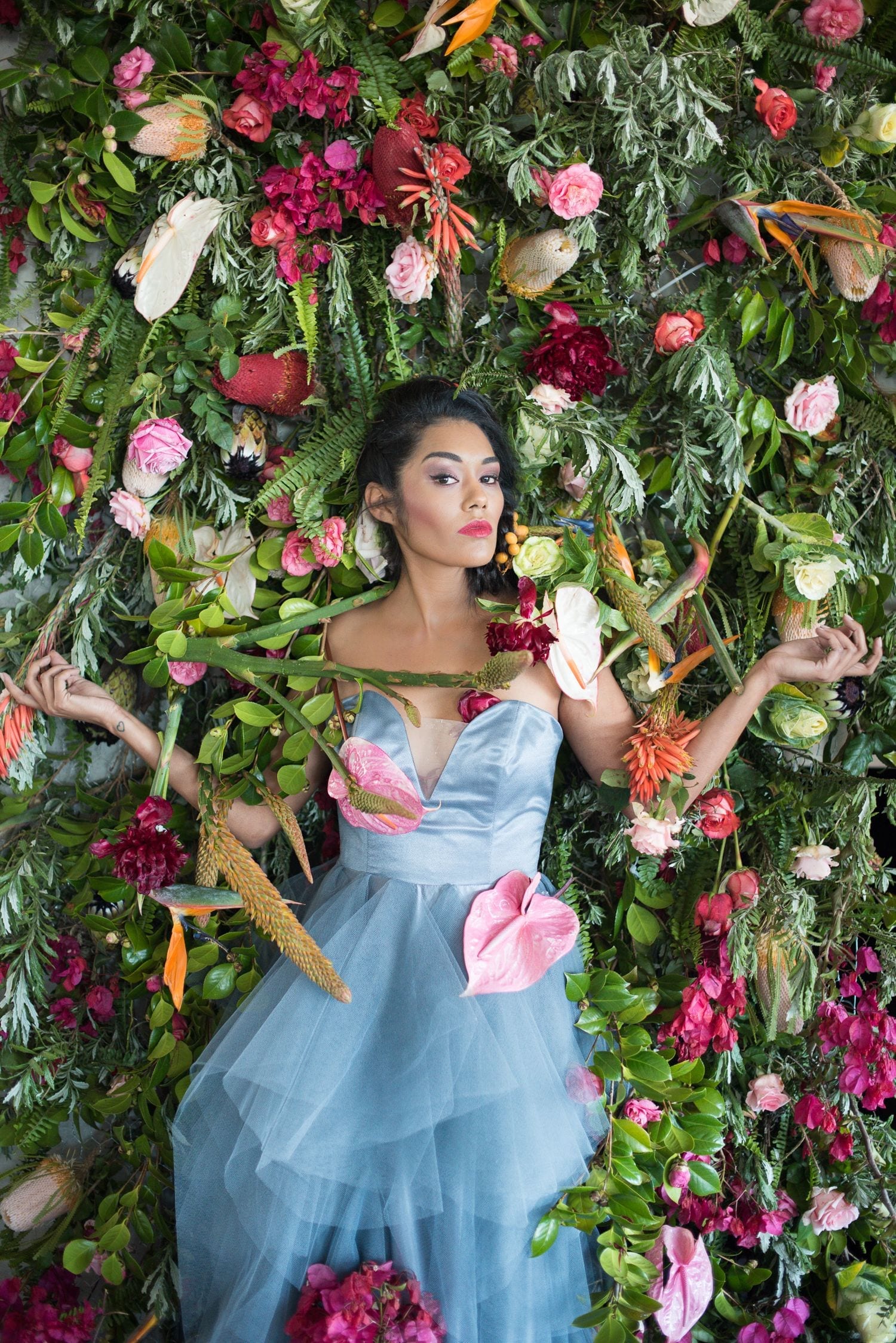 Fashion photography - Woman in blue tulle dress surrounded by vibrant tropical flowers